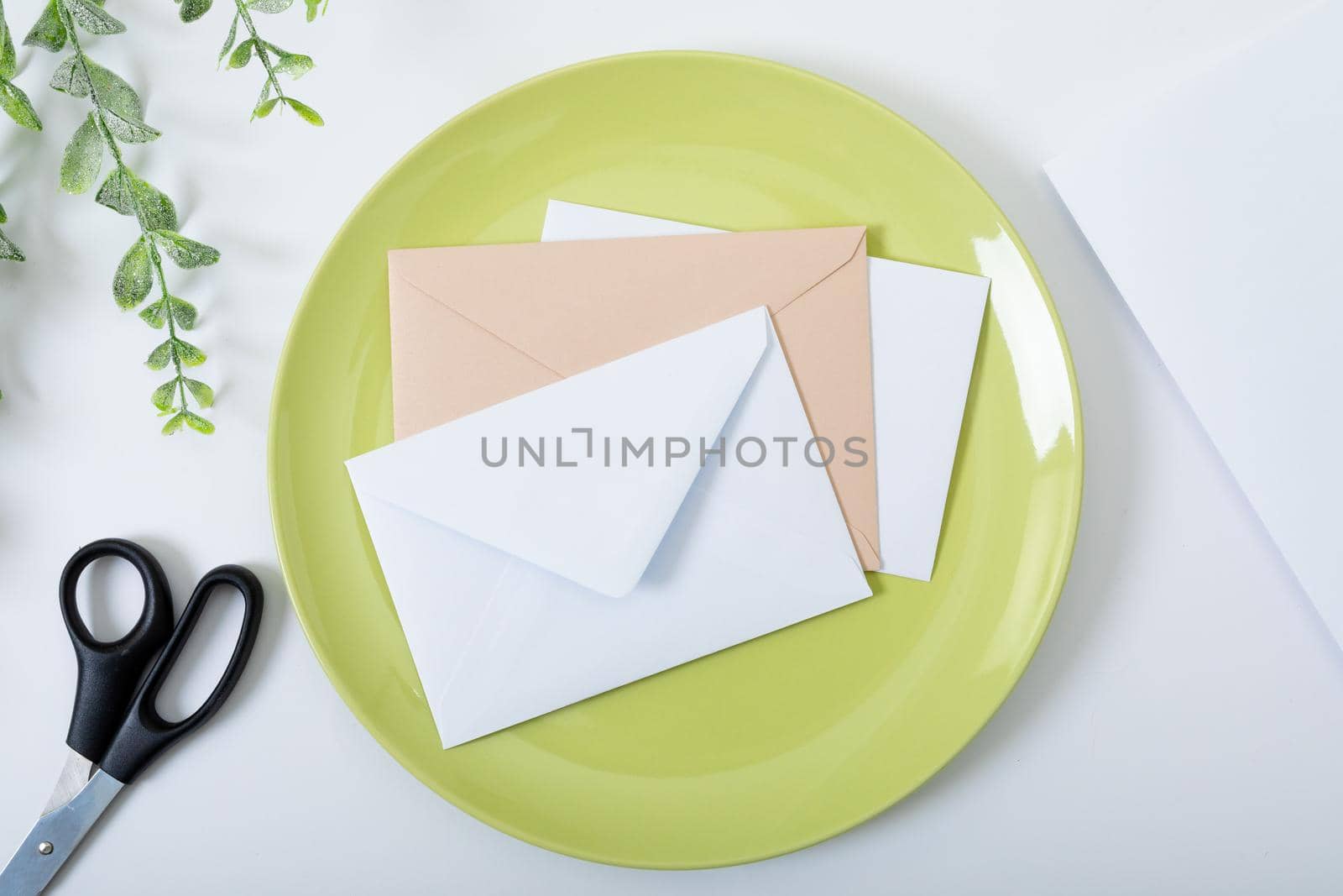Composition of envelopes on green plate, scissors and branches on white background. christmas, communication, tradition and celebration concept.