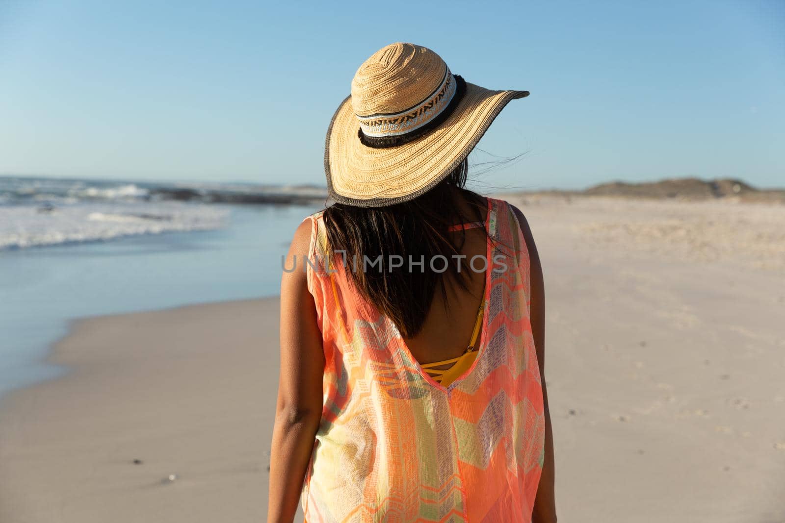 Happy mixed race woman on beach holiday looking away. healthy outdoor leisure time by the sea.