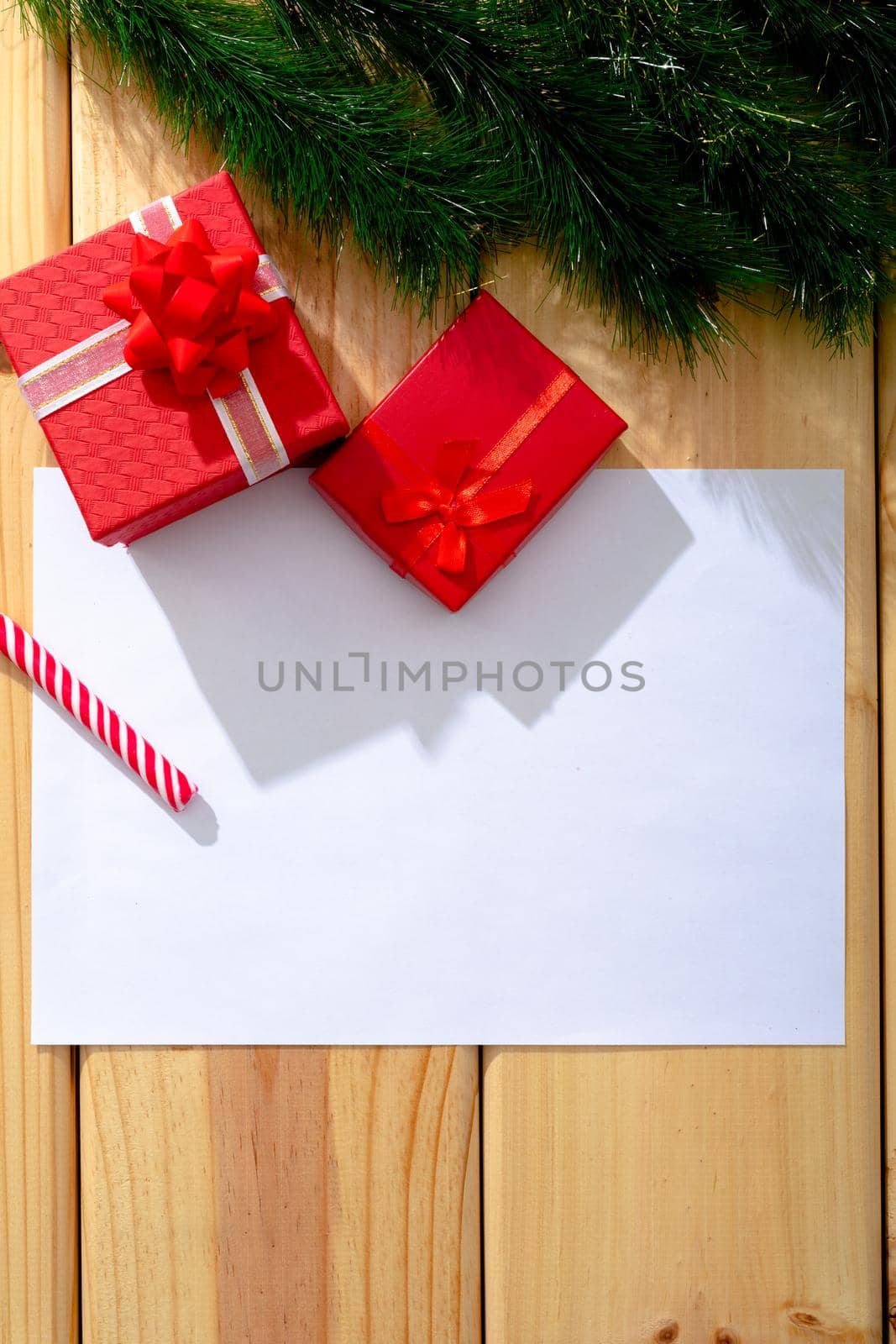 Composition of white card with copy space and fir tree branches with presents on wooden background. christmas, tradition and celebration concept.