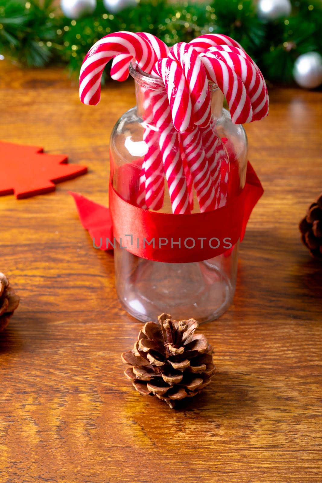 Composition of christmas decorations with candy canes, pine cones and garland on wooden background. christmas, tradition and celebration concept.