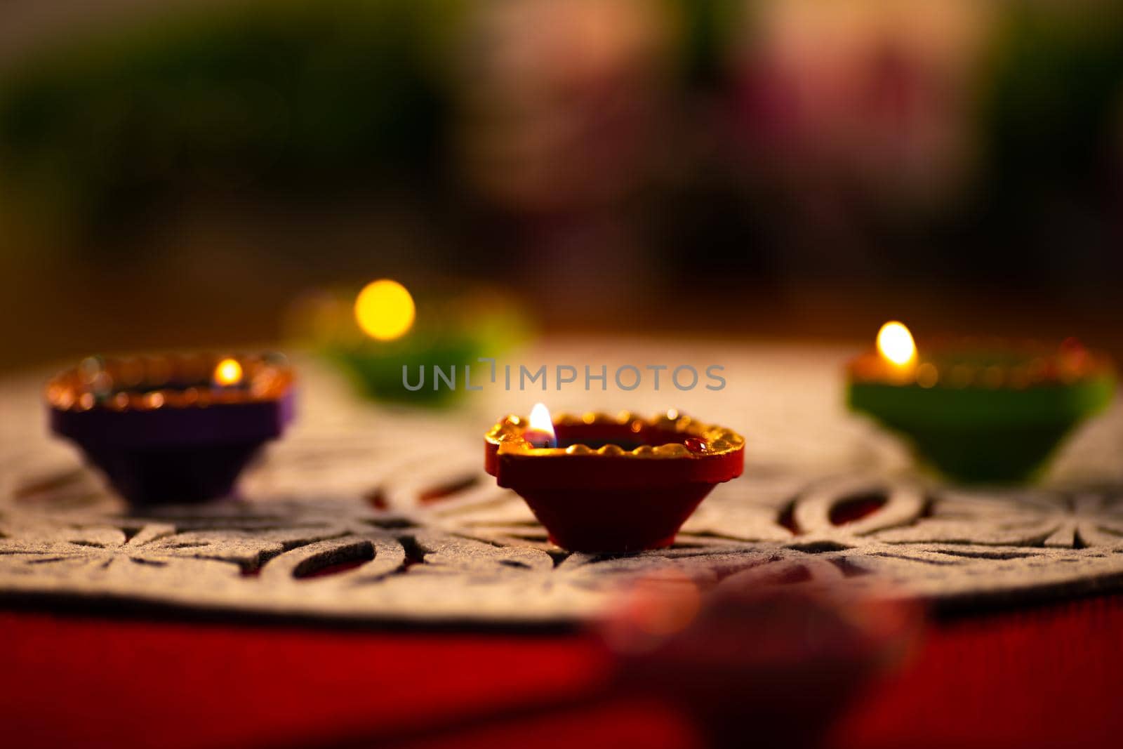 Four lit candles in small decorative clay pots burning on table mat. celebration, religion, tradition and ceremony concept.