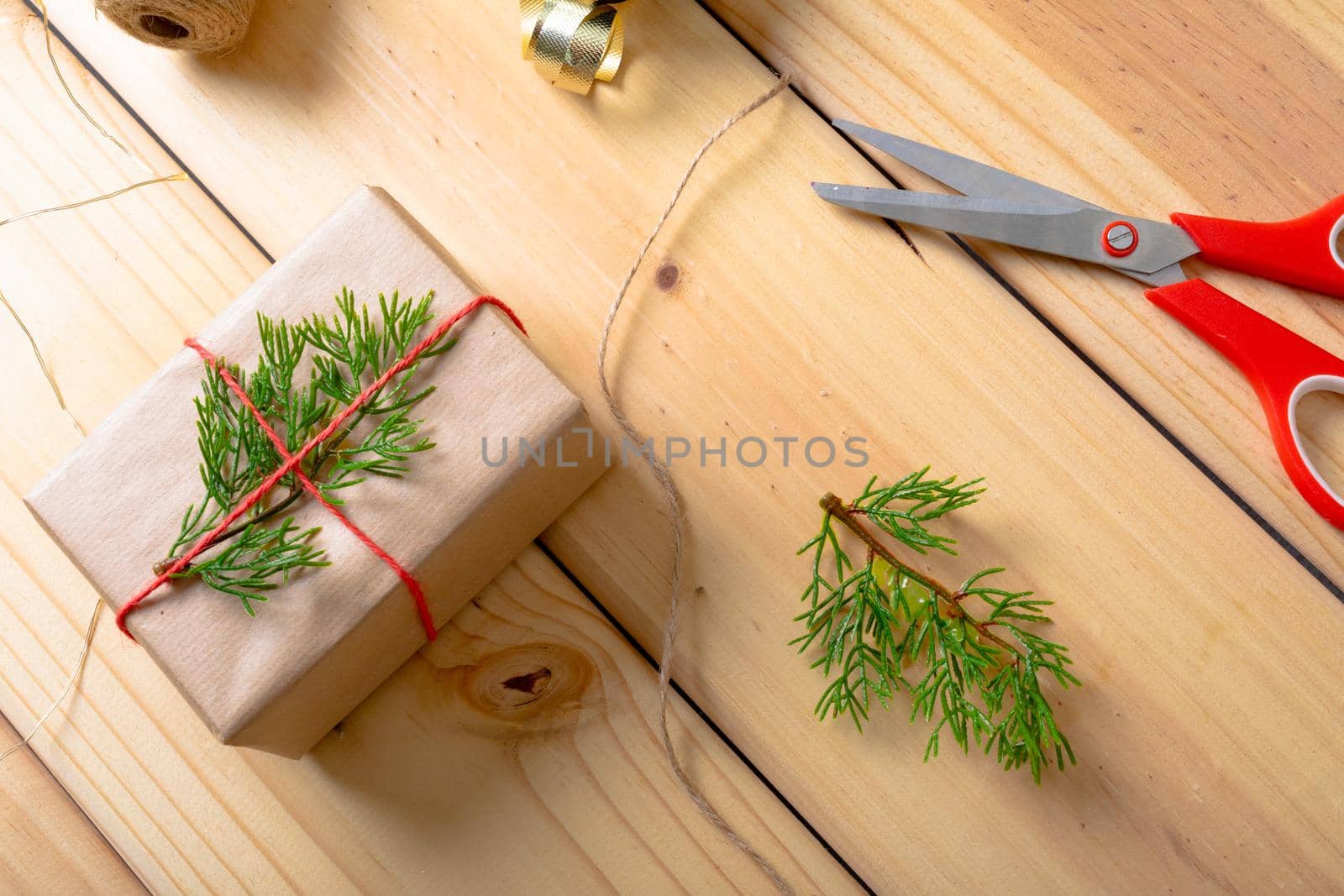 Composition of christmas decorations with present, ribbon, and scissors on wooden background. christmas, tradition and celebration concept.