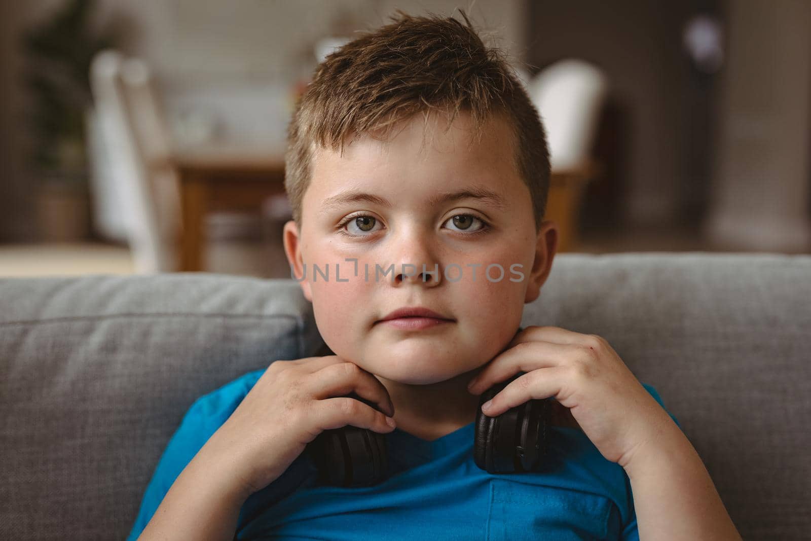 Portrait of caucasian boy wearing headphones sitting on the couch at home. childhood, technology and home concept