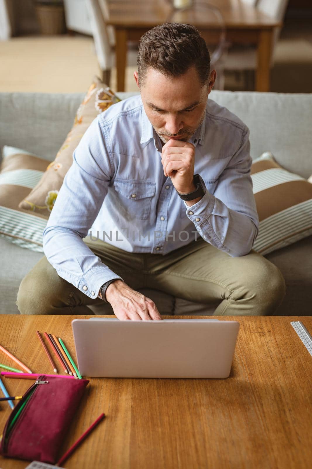 Caucasian man using laptop sitting on the couch at home by Wavebreakmedia