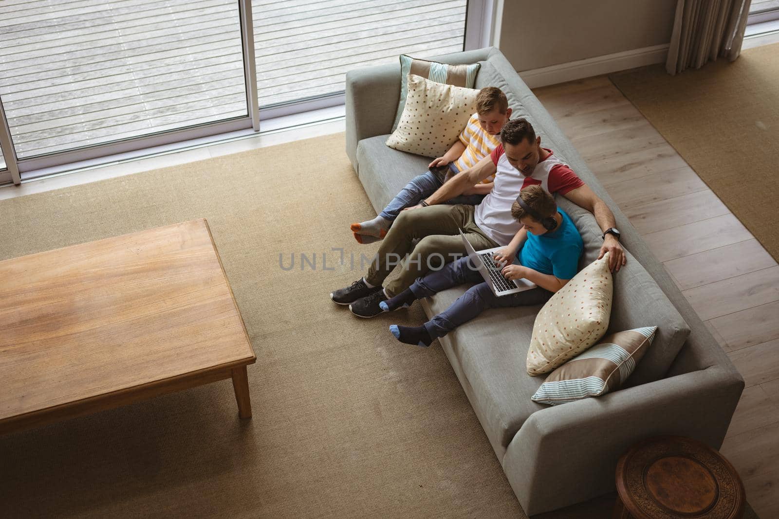 Overhead view of caucasian father and two sons using laptop and digital tablet at home by Wavebreakmedia