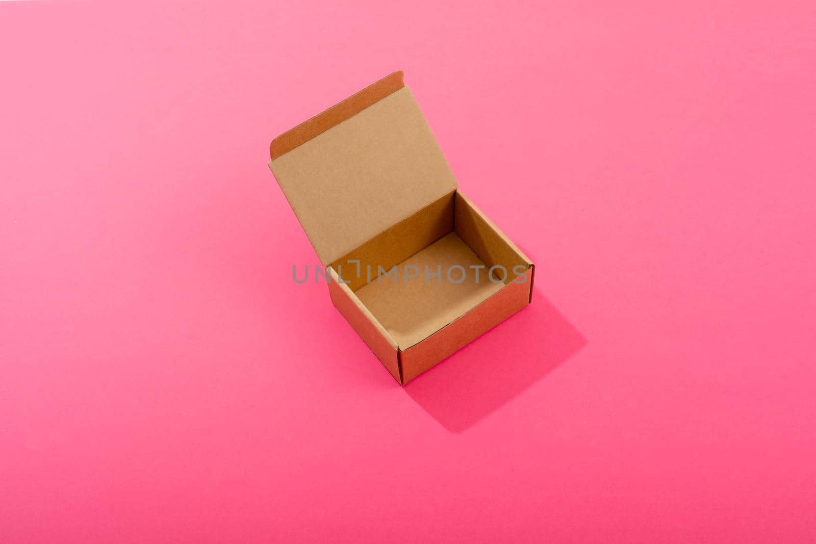 Composition of open empty cardboard gift box on pink background. christmas, gift, tradition and celebration concept.