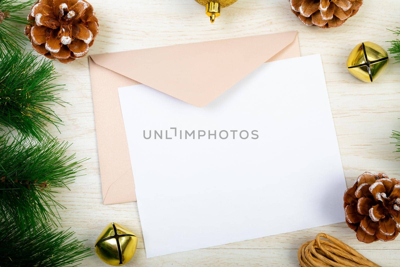Composition of white card with copy space, envelope and christmas decorations on wooden background. christmas, communication, tradition and celebration concept.