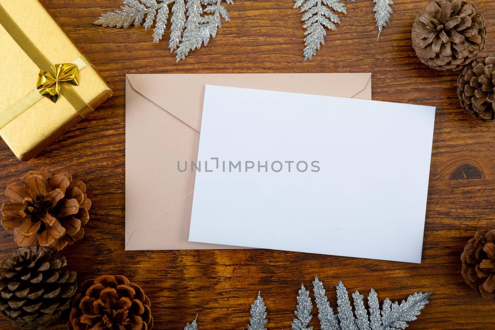 Composition of white card with copy space, envelope and christmas decorations on wooden background. christmas, communication, tradition and celebration concept.
