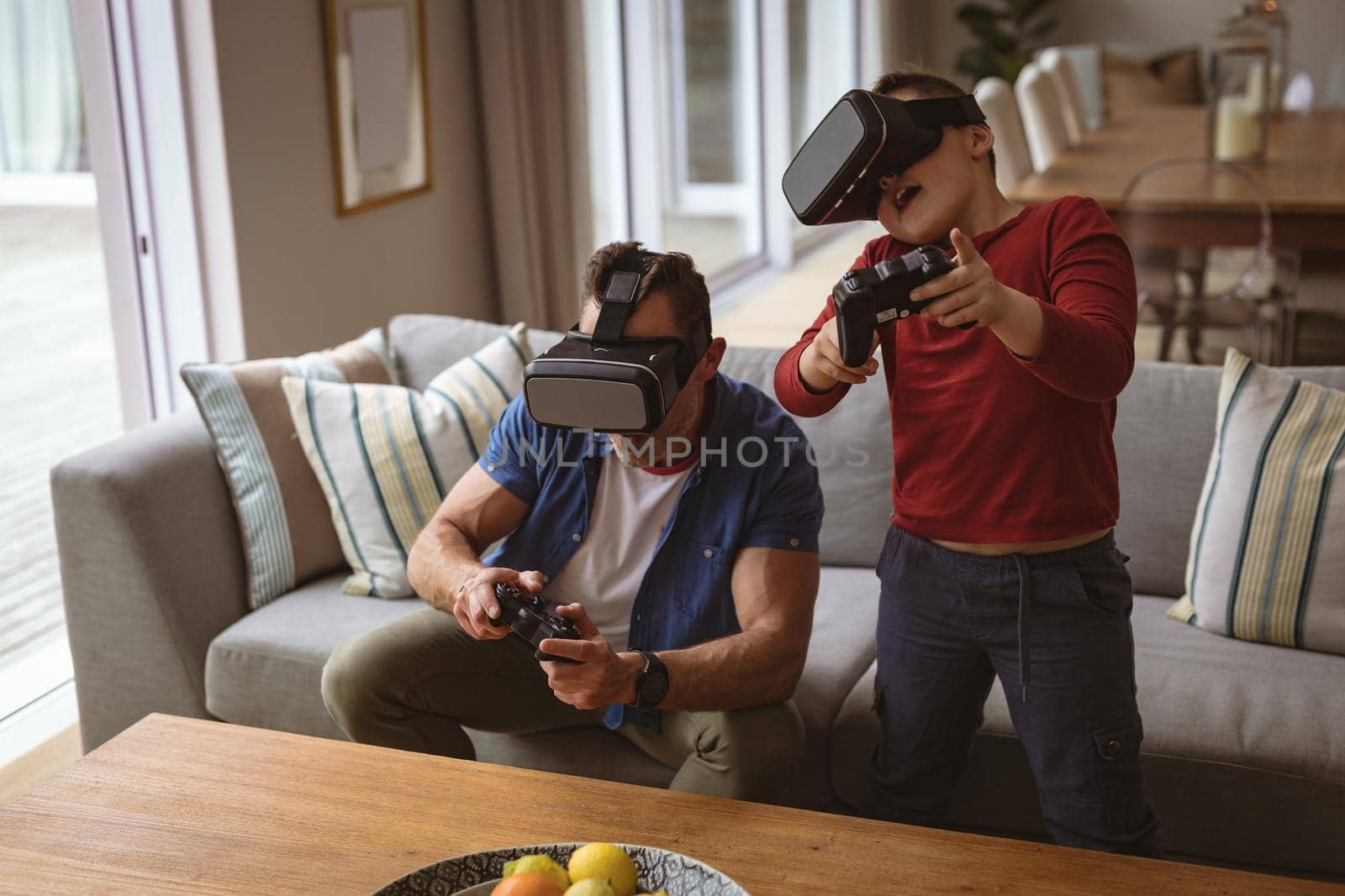 Caucasian father and son wearing vr headsets playing video games at home. gaming and entertainment concept
