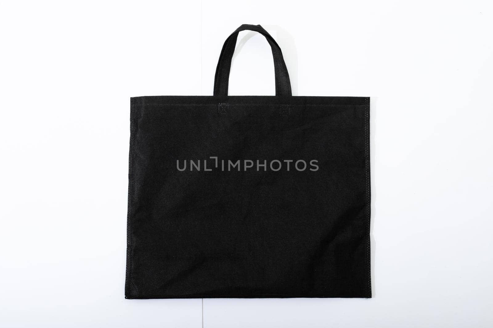 Composition of empty black canvas shopping bag lying flat on white background by Wavebreakmedia