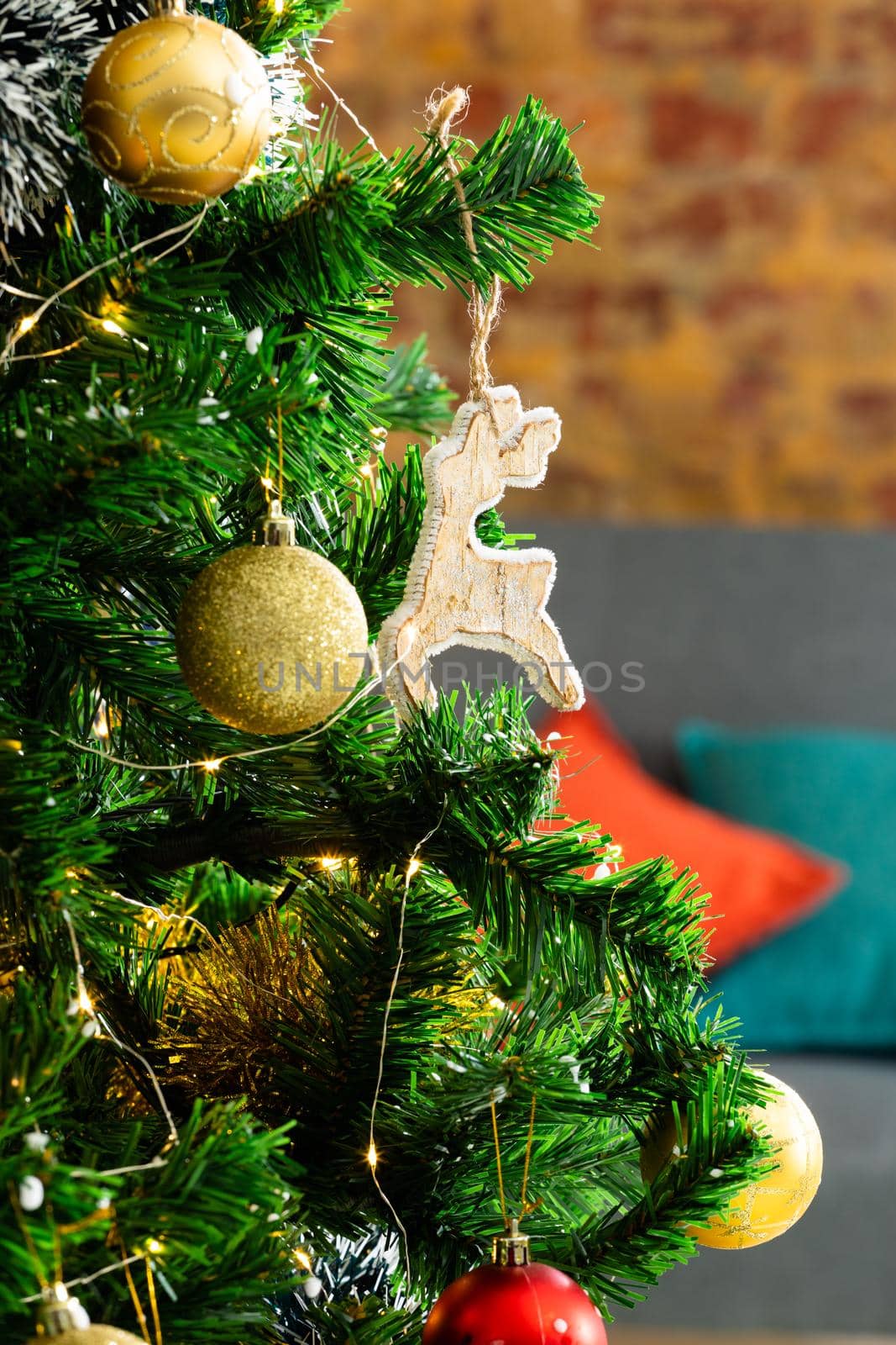 Composition of christmas tree with gold baubles and reindeer on blurred background. christmas, tradition and celebration concept.