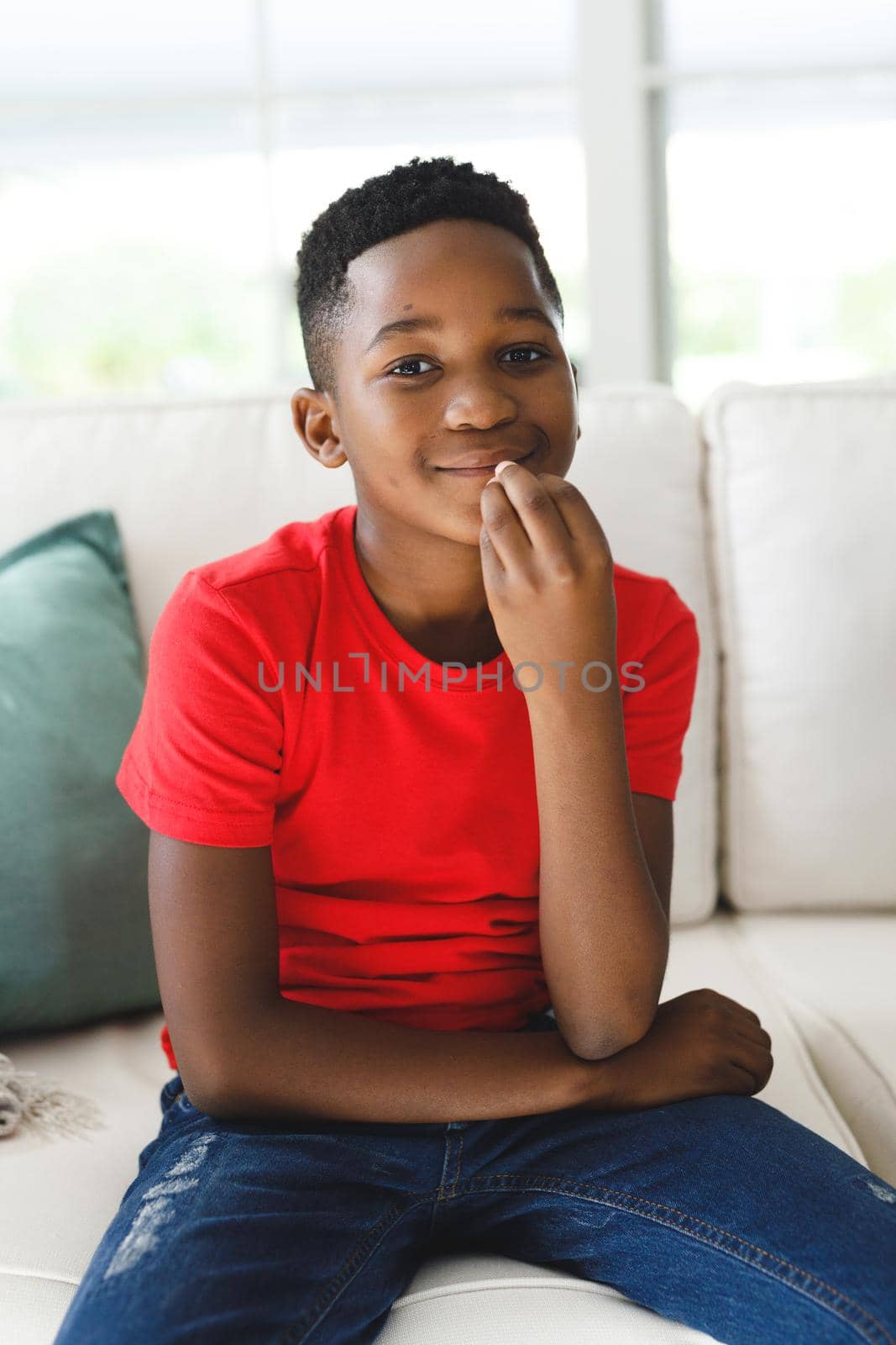 Portrait of smiling african american boy sitting on couch in living room talking sign language by Wavebreakmedia