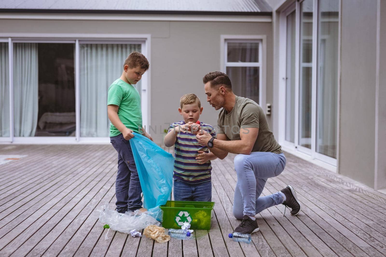 Caucasian father and two sons collecting plastic materials in a bag outdoors by Wavebreakmedia