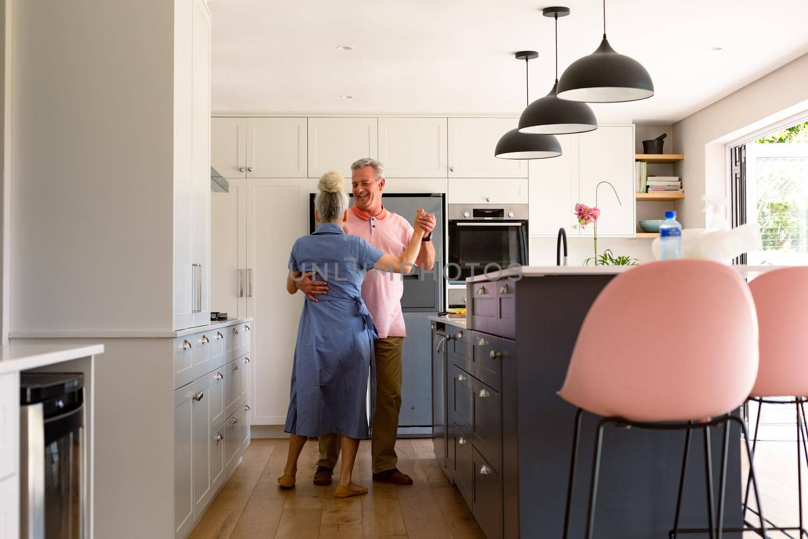 Happy caucasian senior couple dancing together in kitchen and having fun by Wavebreakmedia