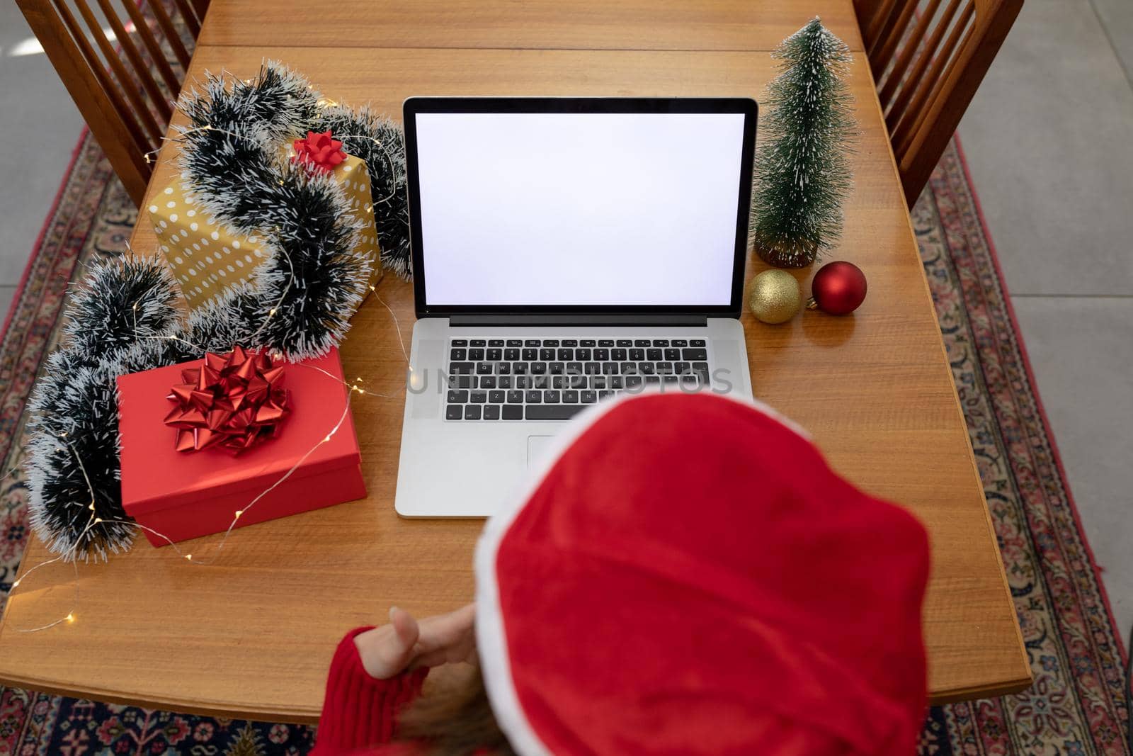 Caucasian woman wearing santa hat having video call on laptop with copy space at christmas time. christmas, festivity and communication technology at home.