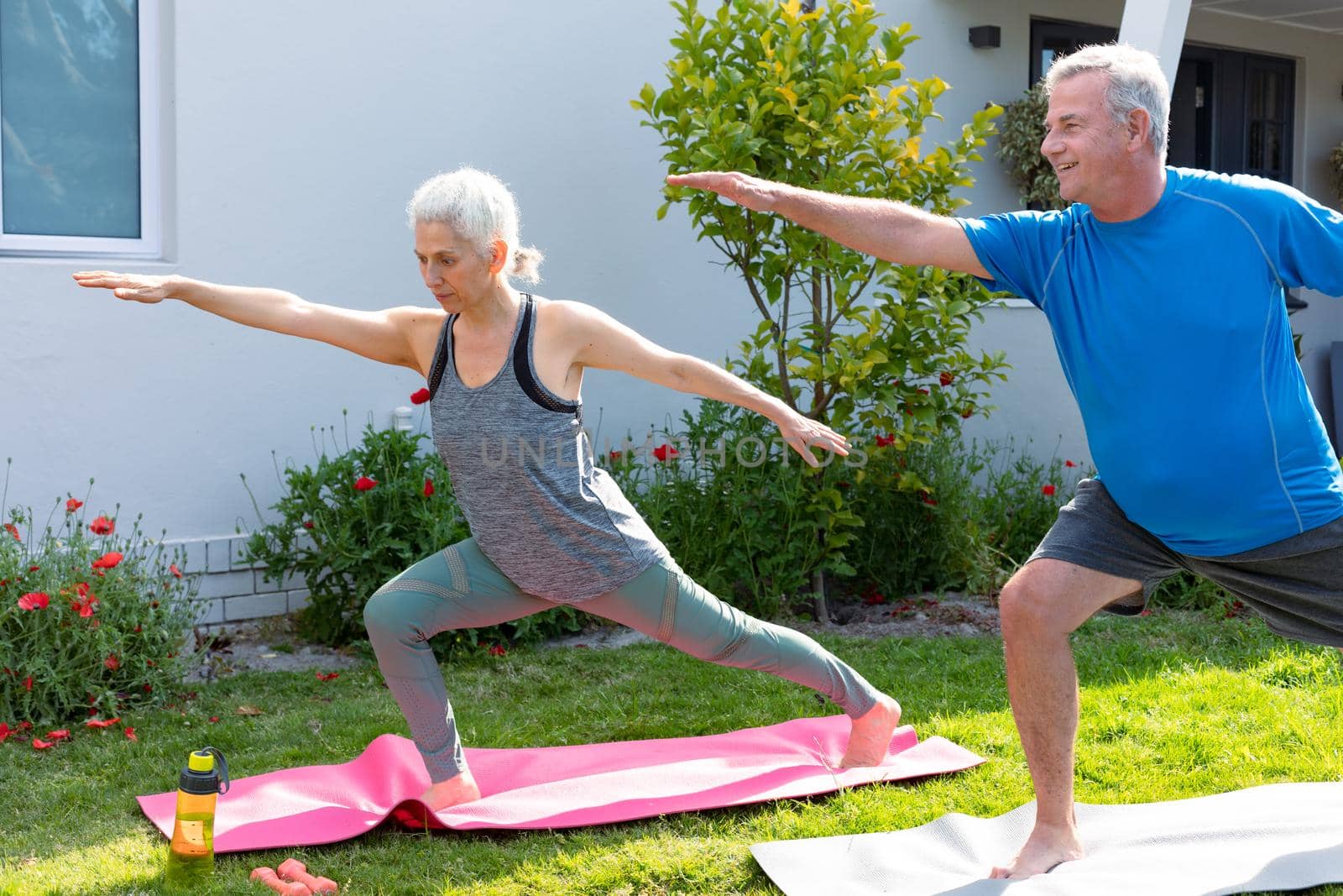 Happy caucasian senior couple practicing yoga together in garden. active and healthy retirement lifestyle at home and garden.