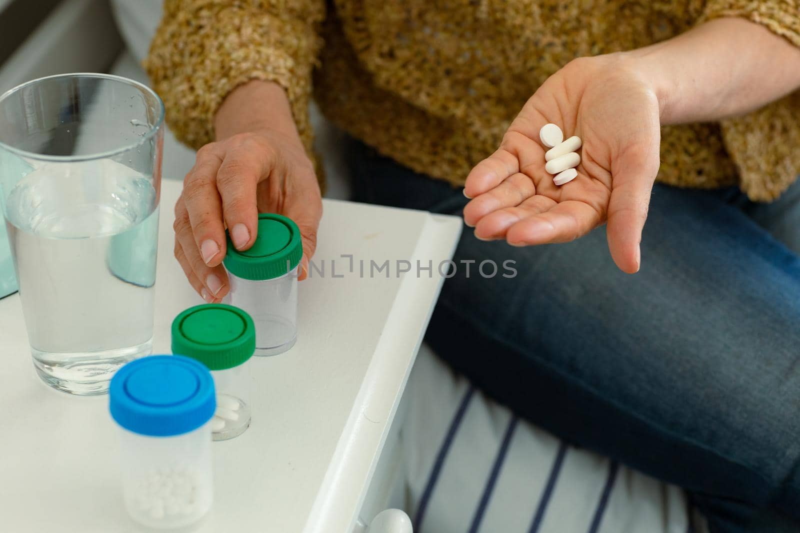 Hands of caucasian senior woman taking pills and sitting on bed. senior health and lifestyle at home.