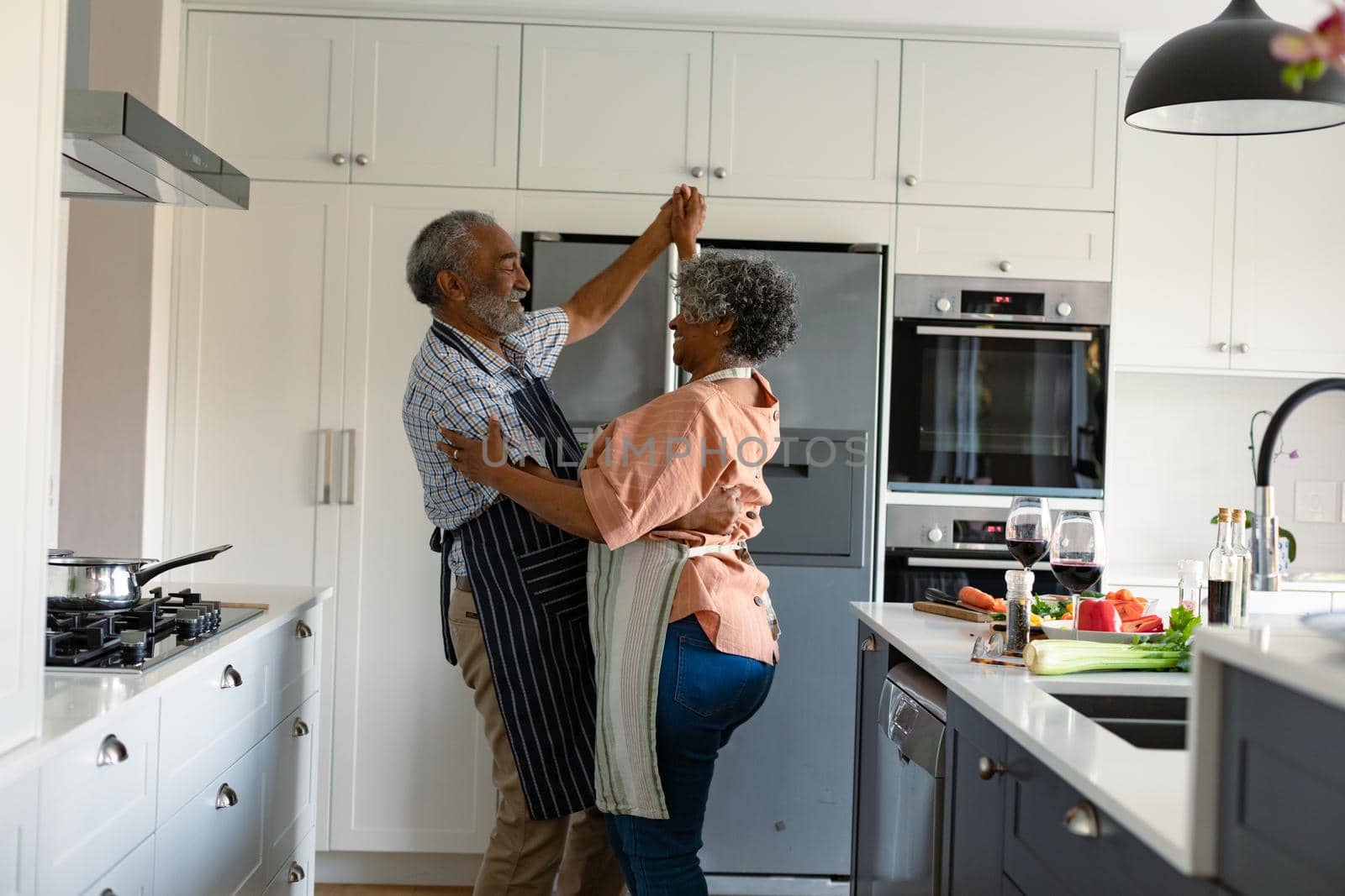 Happy arfican american senior couple dancing together in kitchen and having fun by Wavebreakmedia
