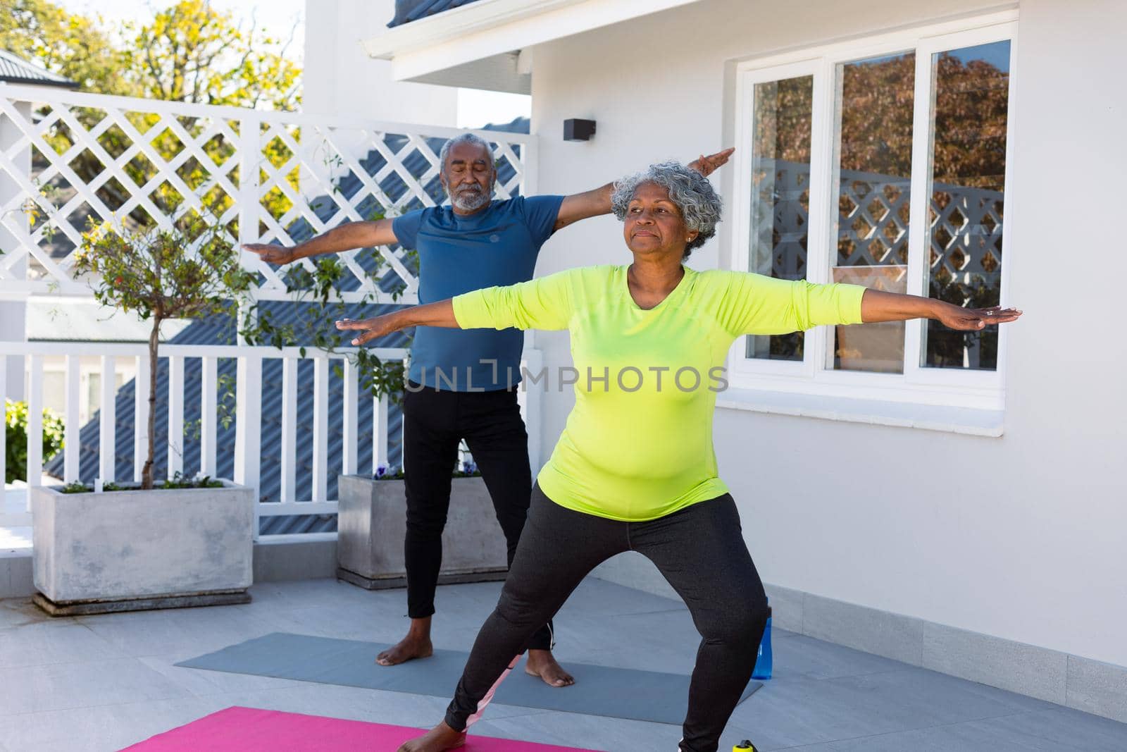 Focused african american senior couple practicing yoga in garden by Wavebreakmedia