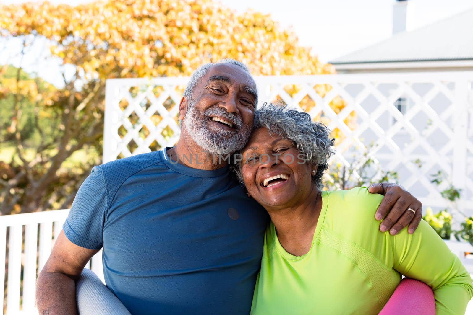 Smiling african american senior couple holding yoga mats in garden and looking at camera. active and healthy retirement lifestyle at home.