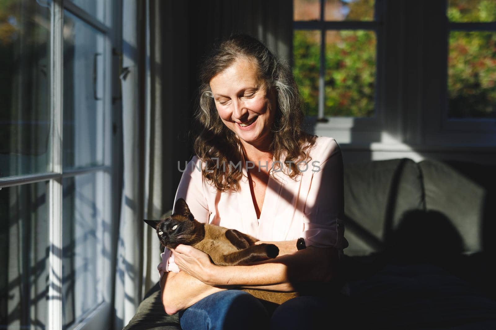 Happy senior caucasian woman in bedroom, holding her pet cat. retirement lifestyle, spending time alone at home.