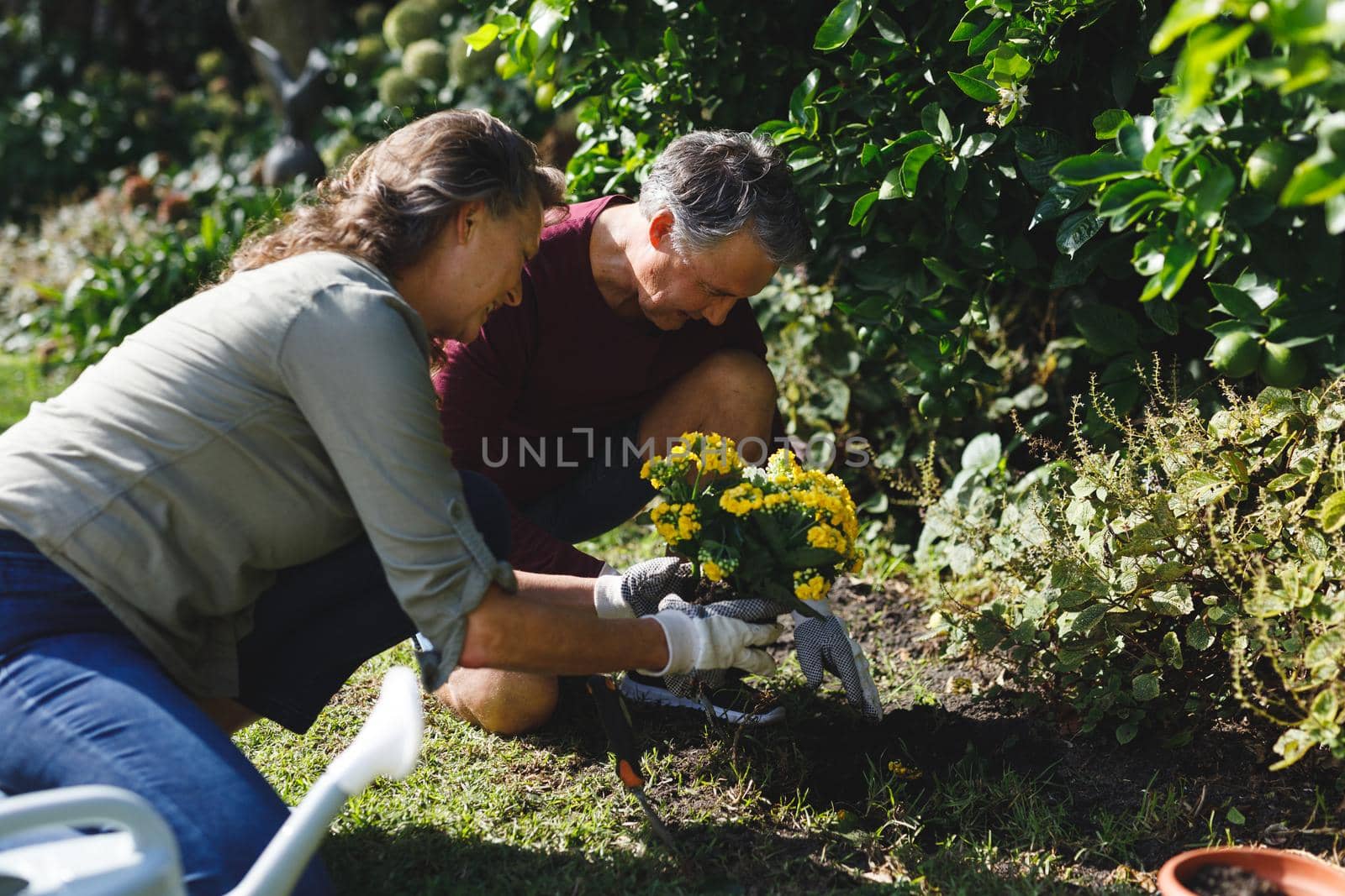 Happy senior caucasian couple gardening together in sunny garden by Wavebreakmedia