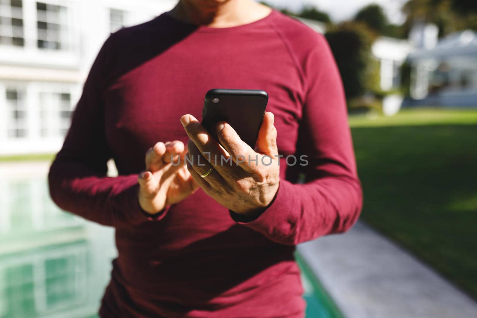 Mid section of senior caucasian man using smartphone in sunny garden by Wavebreakmedia