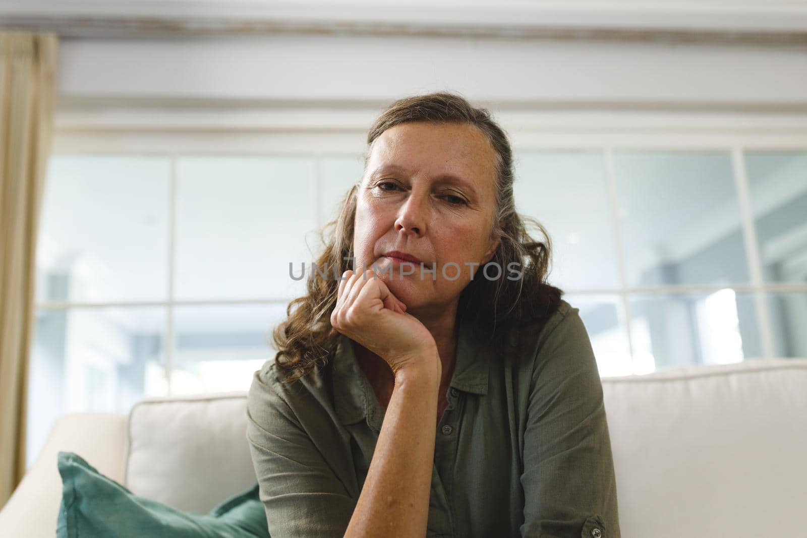 Senior caucasian woman in living room, sitting on sofa, listening during video call. retirement lifestyle, spending time at home with technology.