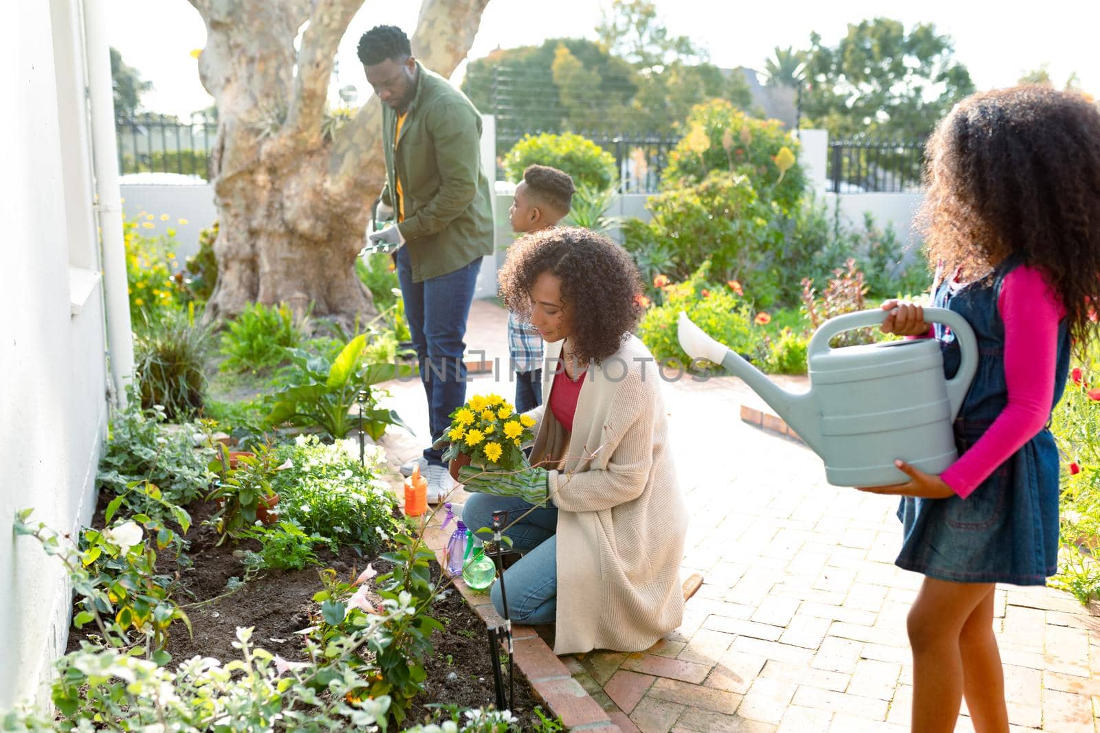 Happy african american family gardening and watering plants together by Wavebreakmedia