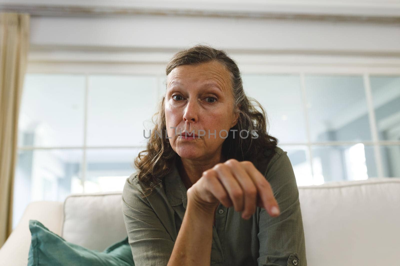 Senior caucasian woman in living room, sitting on sofa, talking and gesturing during video call. retirement lifestyle, spending time at home with technology.