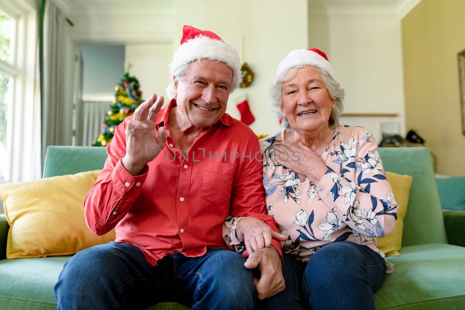 Happy caucasian senior couple in santa hats having video call at christmas time. christmas, festivity and communication technology.