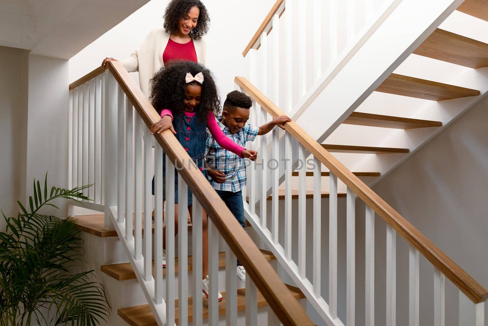 Happy african american mother and children walking downstairs by Wavebreakmedia