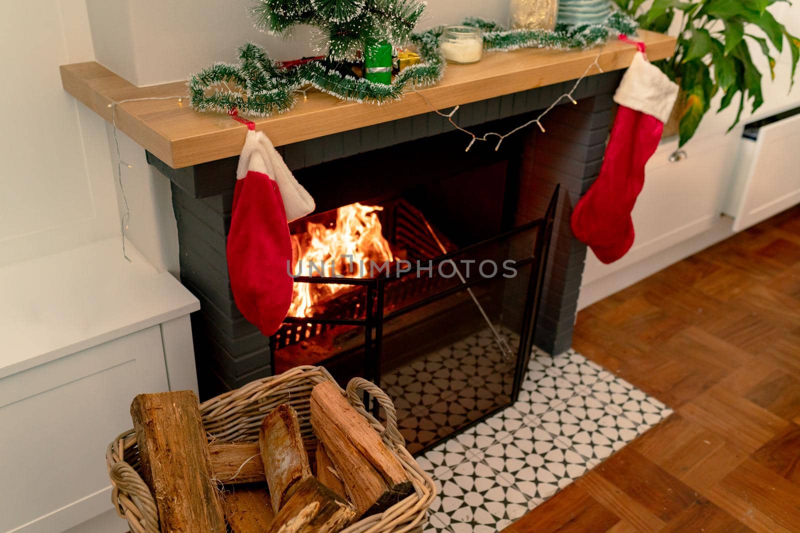 Logs of wood in basket lying at fireplace wit christmas sock. christmas, festivity and tradition at home.