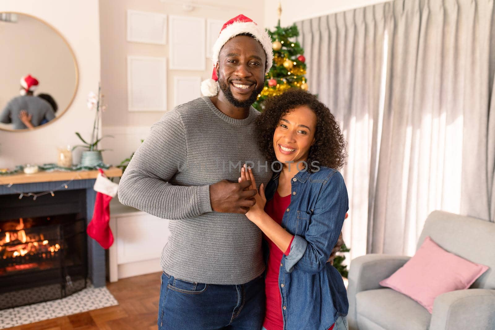 Happy african american couple embracing, christmas decorations in background. family christmas time and festivity together at home.