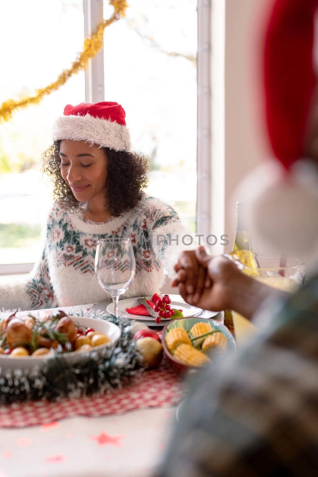 African american woman and her partner holding hands over christmas table by Wavebreakmedia