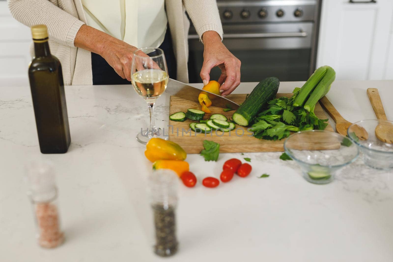 Midsection of senior caucasian woman in modern kitchen, chopping vegetables by Wavebreakmedia