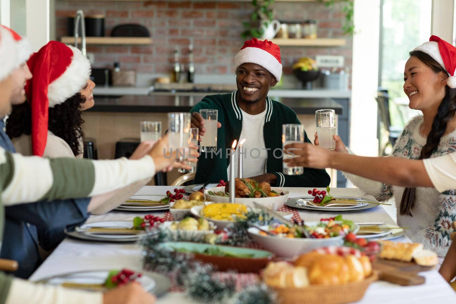 Group of happy diverse female and male friends toasting, celebrating christmas at home. christmas festivities, celebrating at home with friends.