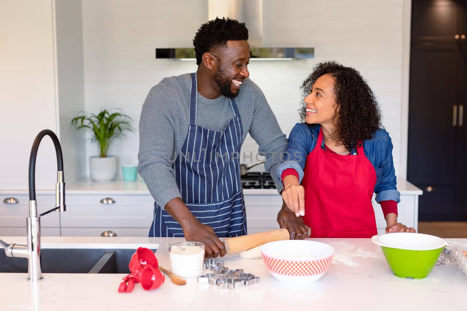 Happy african american couple wearing aprons, baking together. family time, having fun together at home.