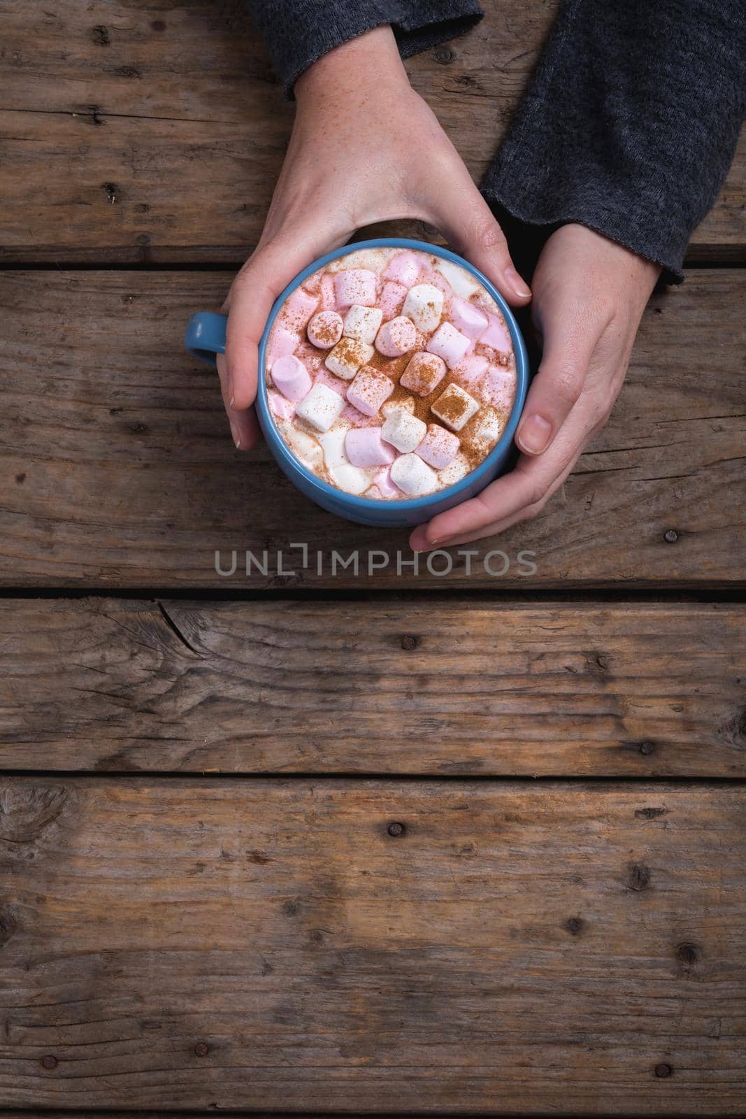Hands of woman holding mug of hot chocolate drink with copy space at wooden table in cafe. lifestyle and cafe culture.