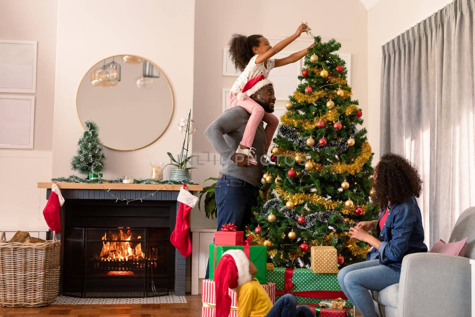 Happy african american parents and daughter decorating christmas tree by Wavebreakmedia