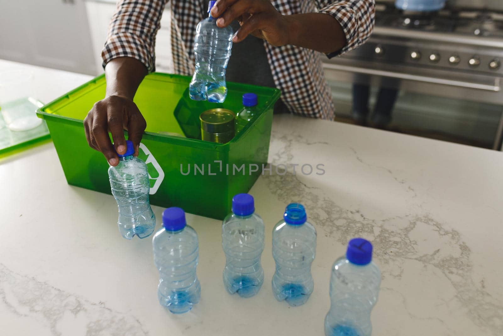 Hands of african american man in kitchen sorting rubbish into crate for recycling by Wavebreakmedia