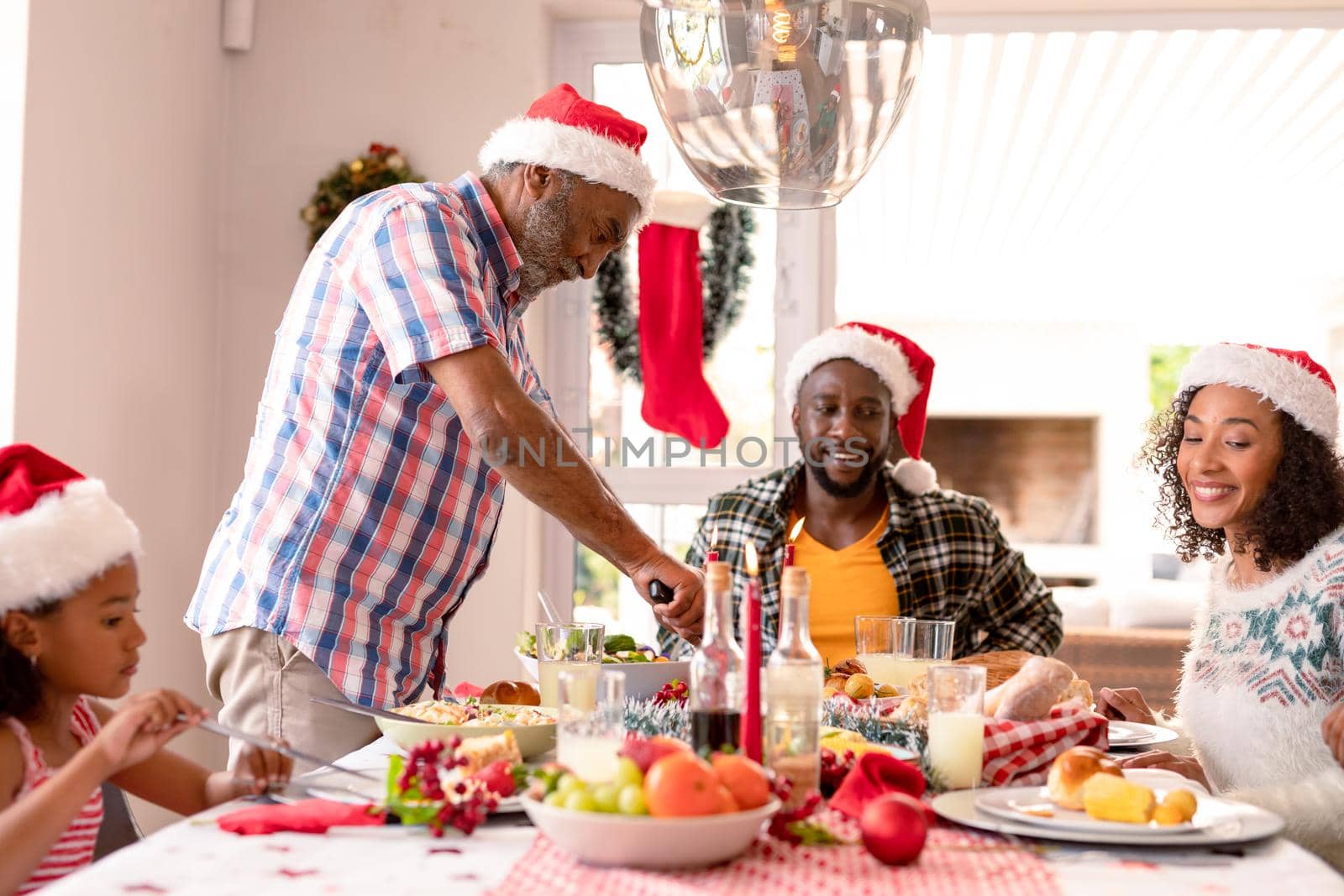 Happy multi generation family wearing santa hats, having christmas meal by Wavebreakmedia