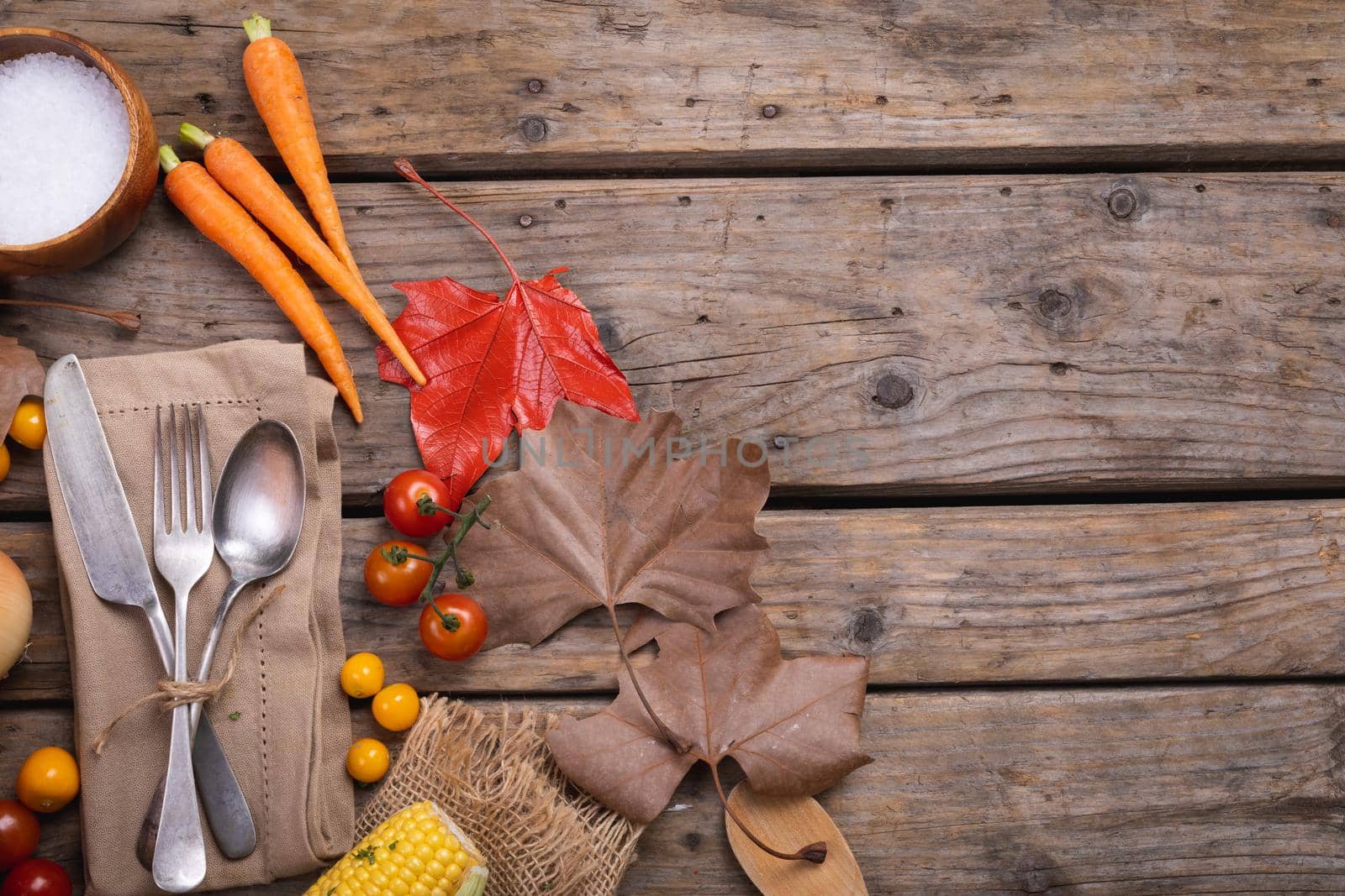 Composition of fall autumn dry leaves, vegetable and cutlery on rustic wooden surface. fall autumn tradition and celebration concept digitally generated image.