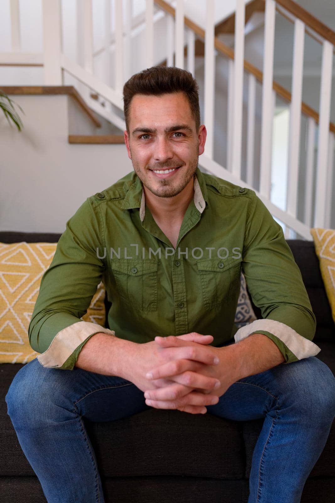 Happy caucasian man sitting on sofa and looking at camera. lifestyle, leisure and spending free time at home.