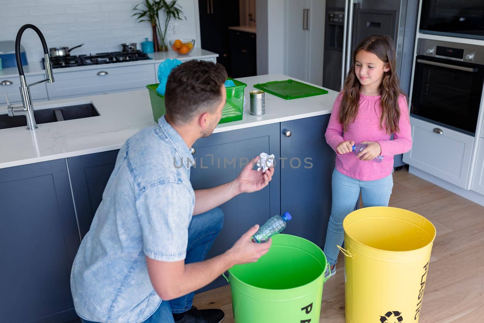 Happy caucasian father and daughter segregating rubbish. recycling, waste selection, spending time together at home.