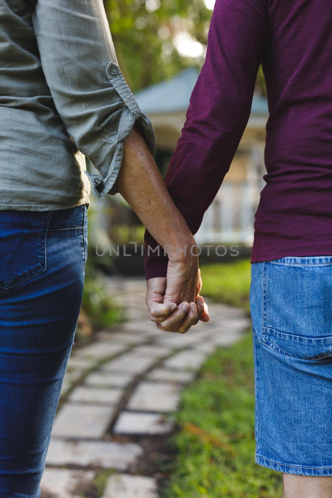 Mid section of senior caucasian couple holding hands in sunny garden by Wavebreakmedia