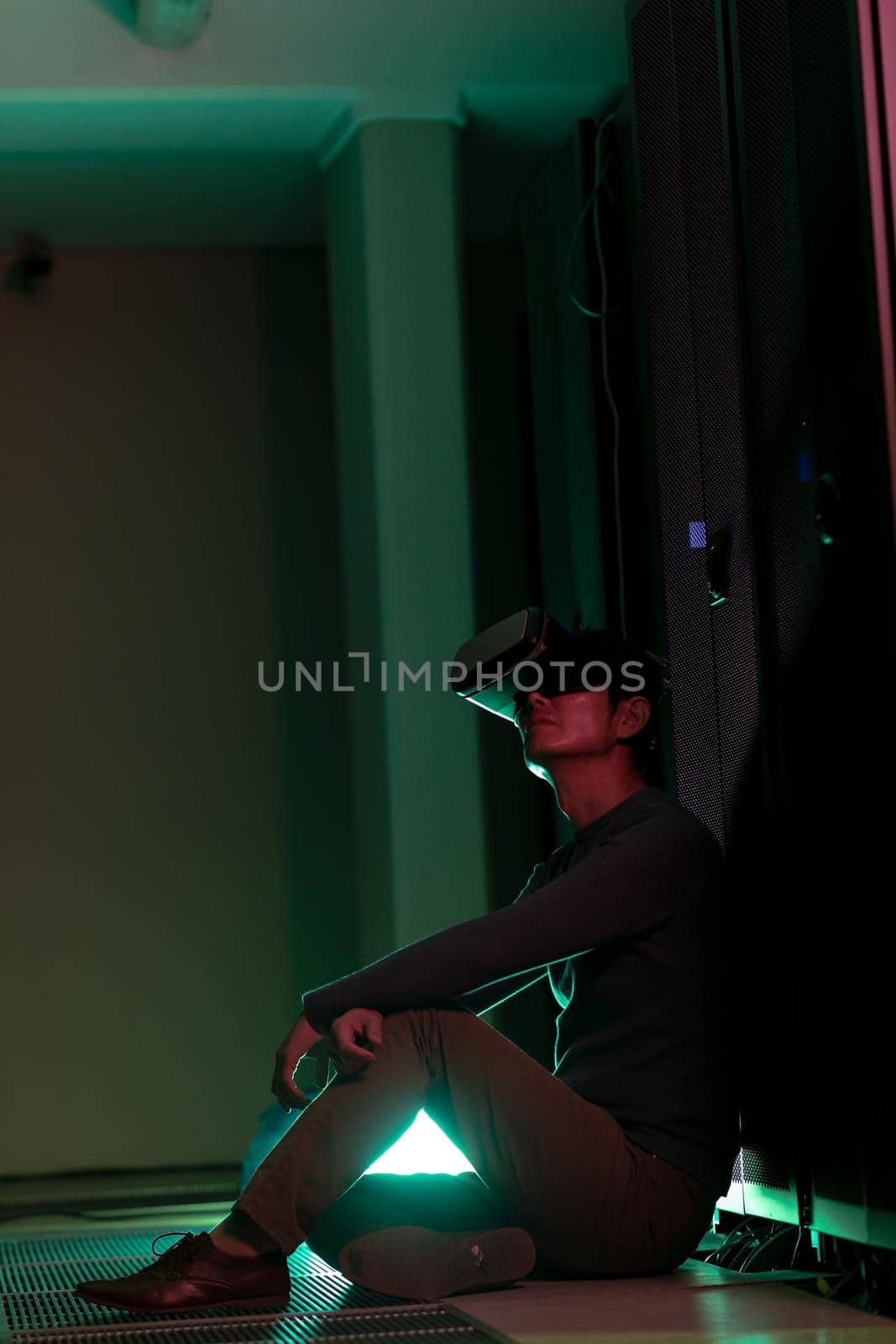 Asian man wearing vr headset while sitting in computer server room. database server and futuristic technology concept