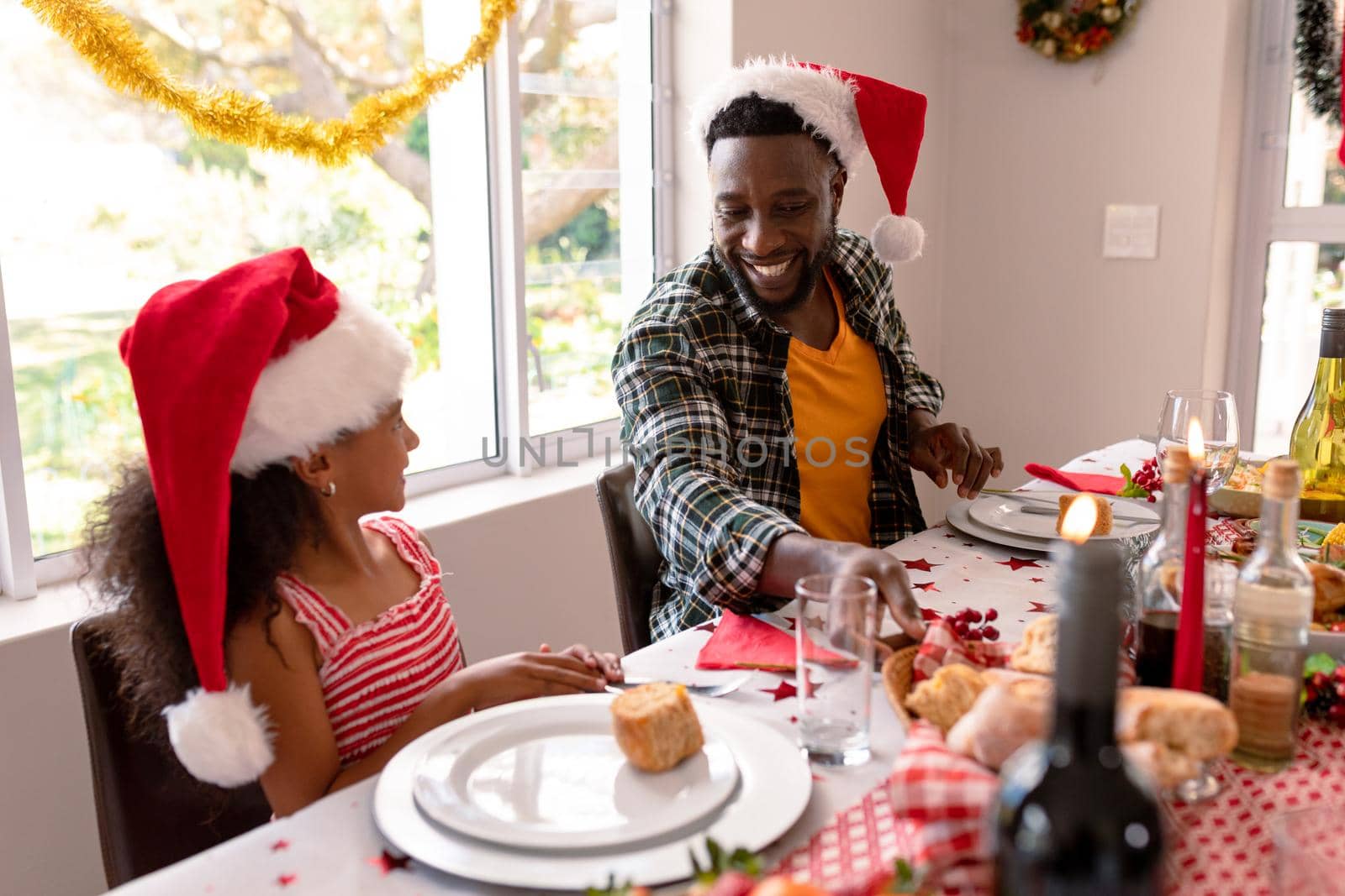 Happy african american father and daughter talking at christmas table. family christmas time and festivity together at home.