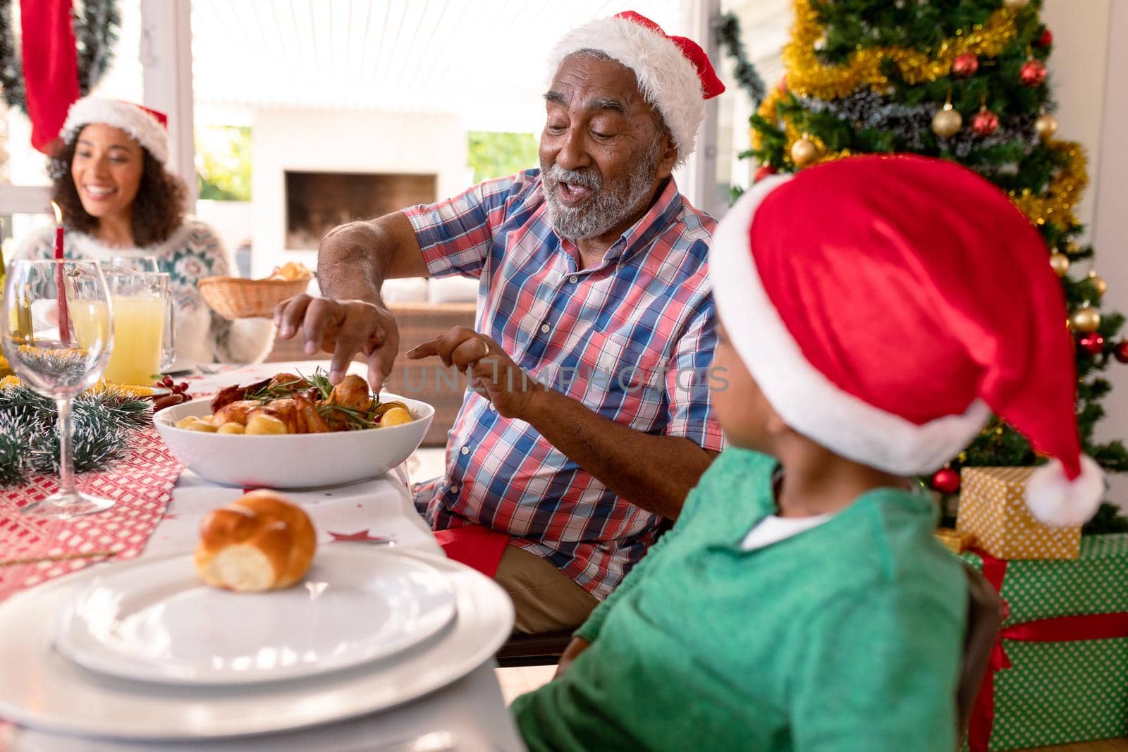 Happy multi generation family wearing santa hats, having christmas meal. family christmas time and festivity together at home.