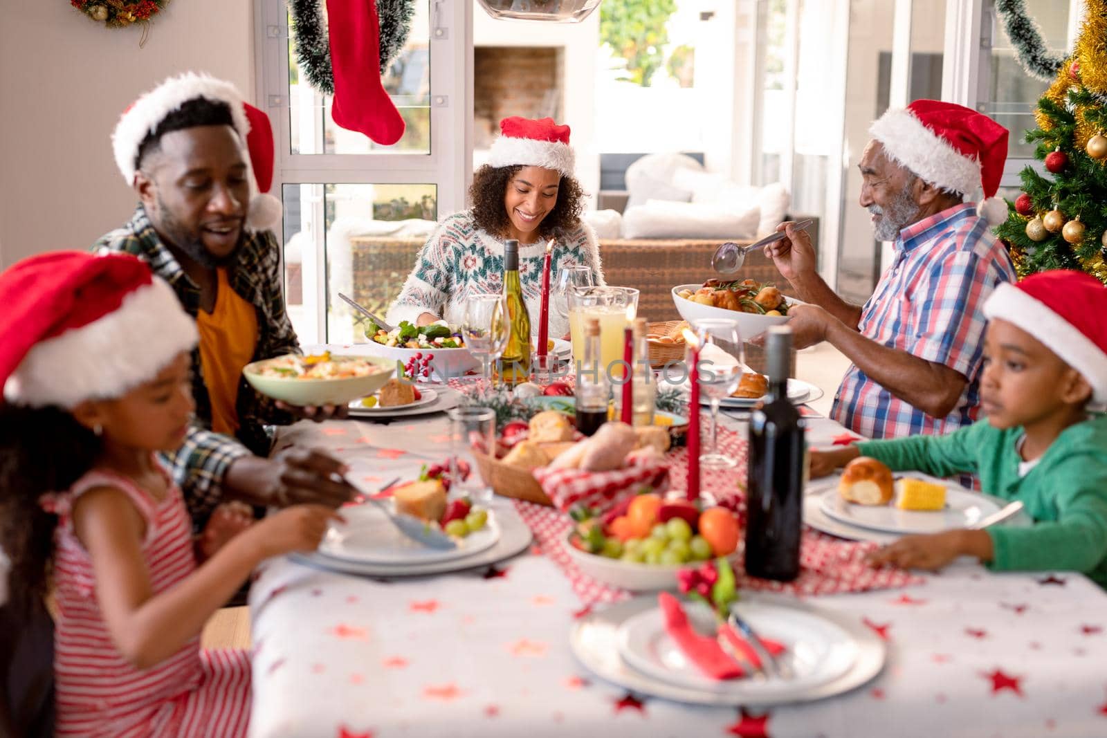 Happy multi generation family wearing santa hats, having christmas meal by Wavebreakmedia